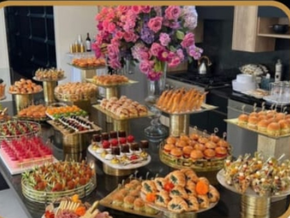 Mesa de canapés surtidos, con arreglo floral y bandejas doradas